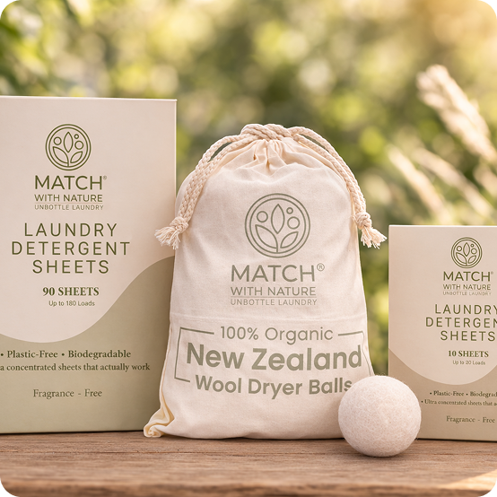 Match with Nature laundry detergent sheets, organic wool dryer balls, and packaging on a wooden surface with a blurred natural background.