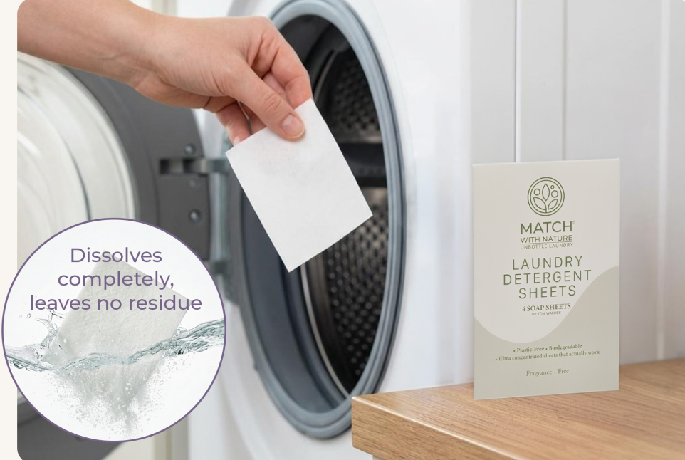 Person holding a laundry detergent sheet with a washing machine in the background and Match with Nature packaging.