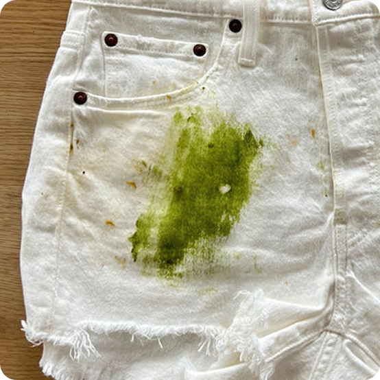 White shorts with a green stain on a wooden surface