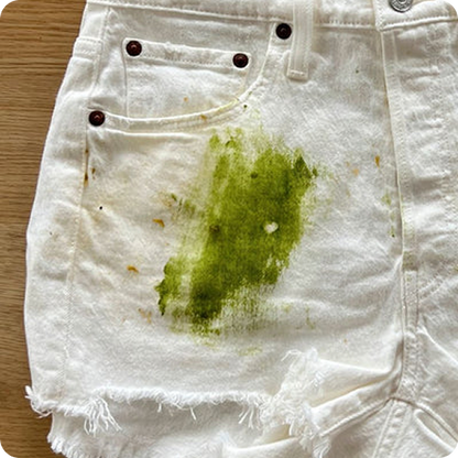 White shorts with a green stain on a wooden surface
